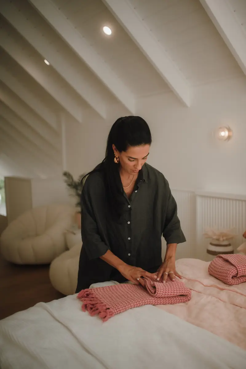 Ive Bitencourt sorting and folding linen on a bed during a decluttering session