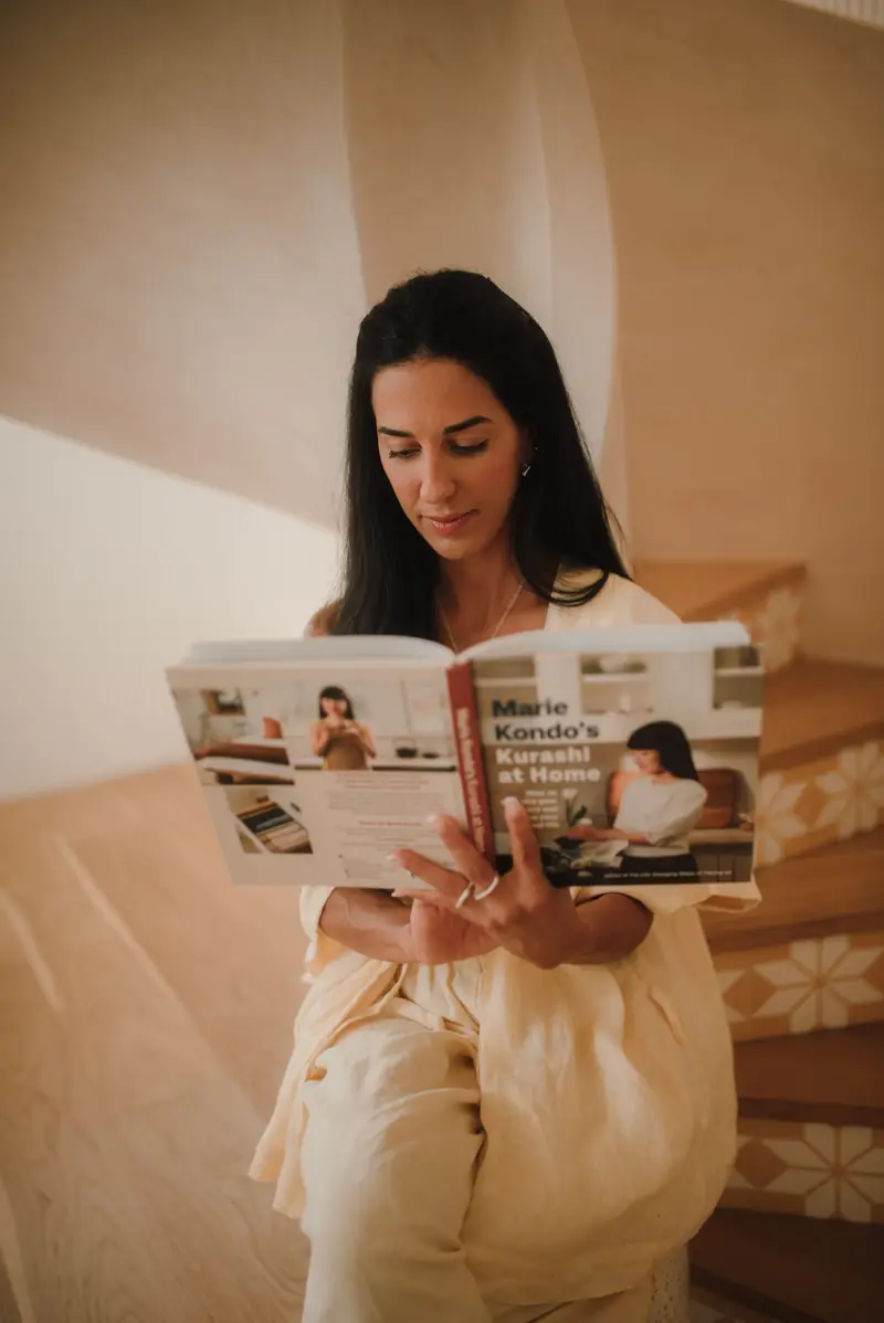 Ive Bitencourt reading a home organising book on a staircase